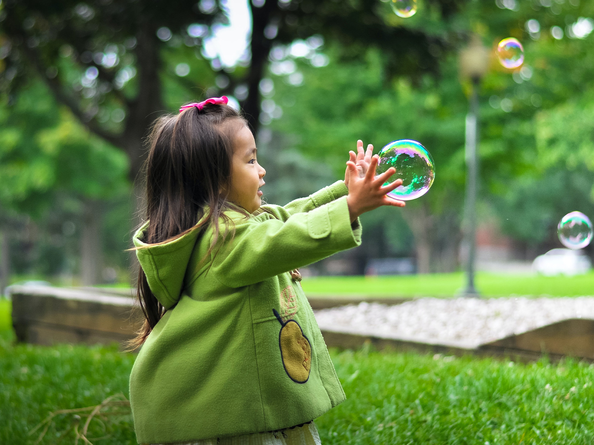 Young girl playing with bubbles in a park