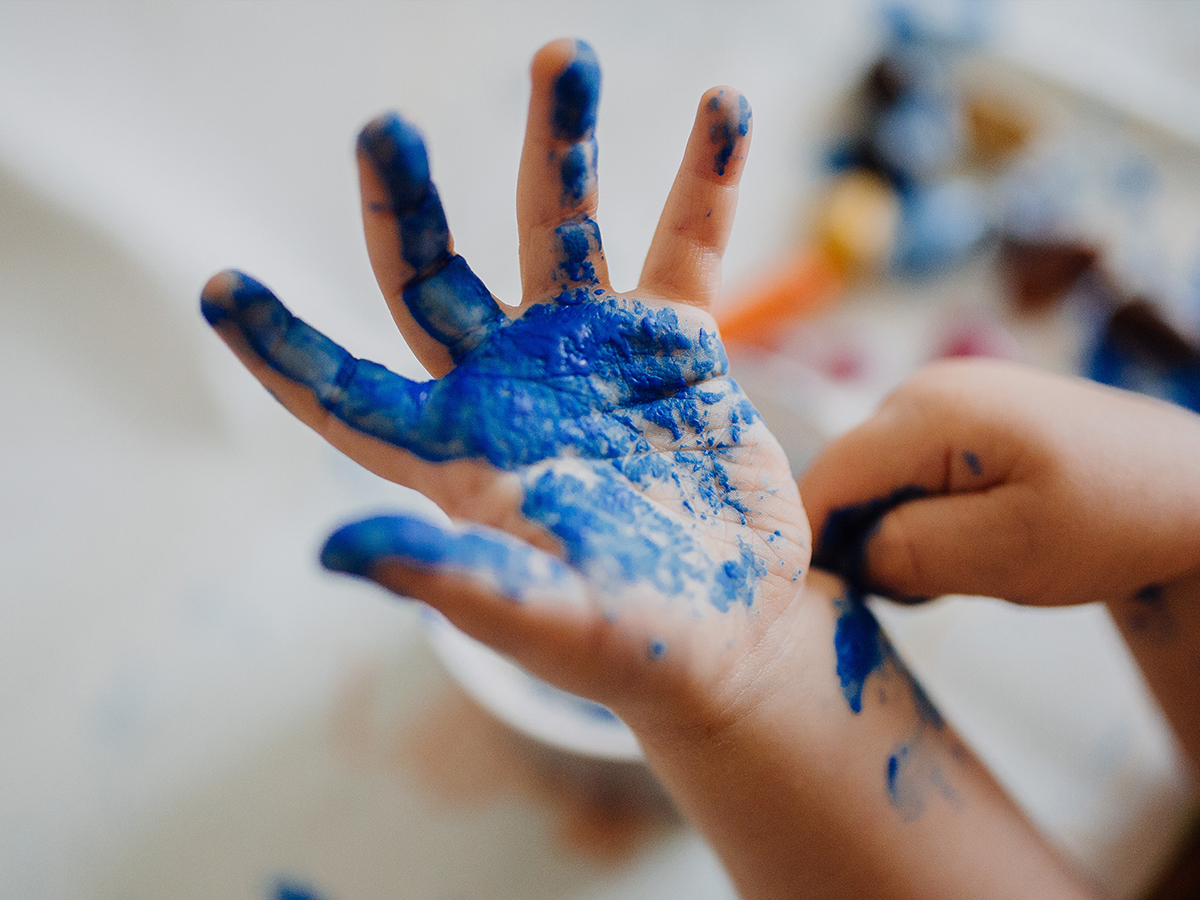 Child with blue paint on their hand