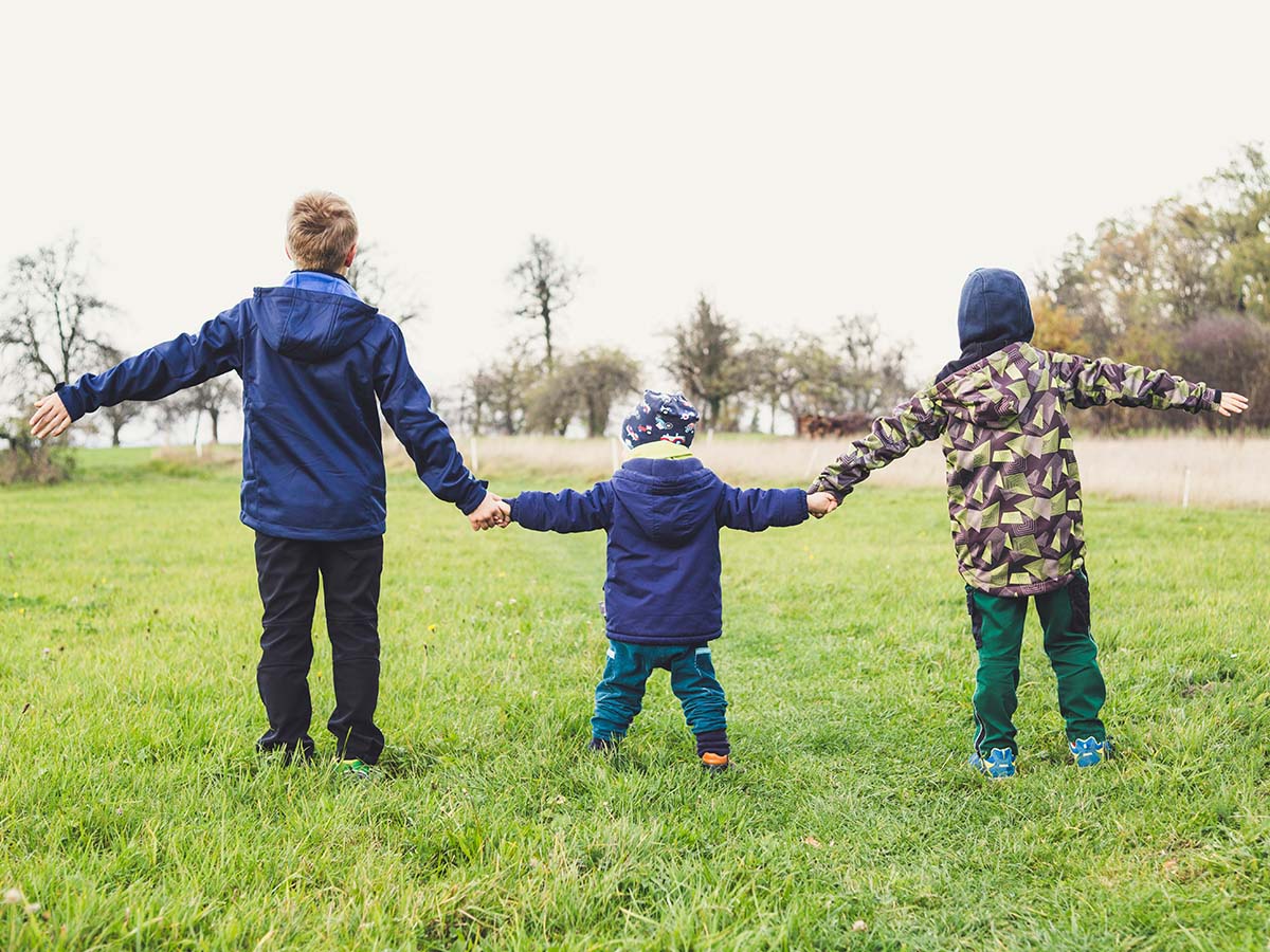 Three children holding hands with the youngest in the middle