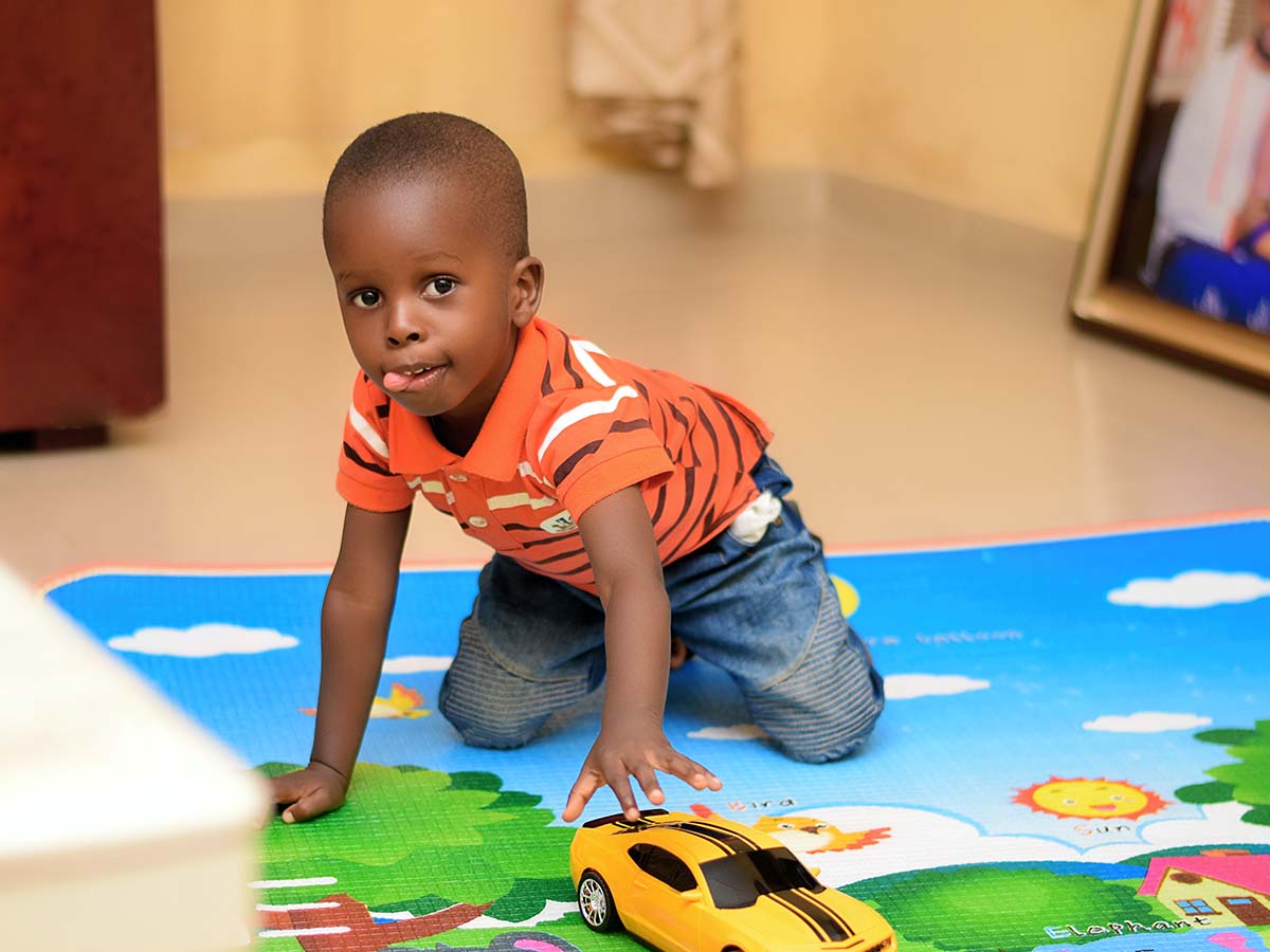 A preschool boy playing on a mat