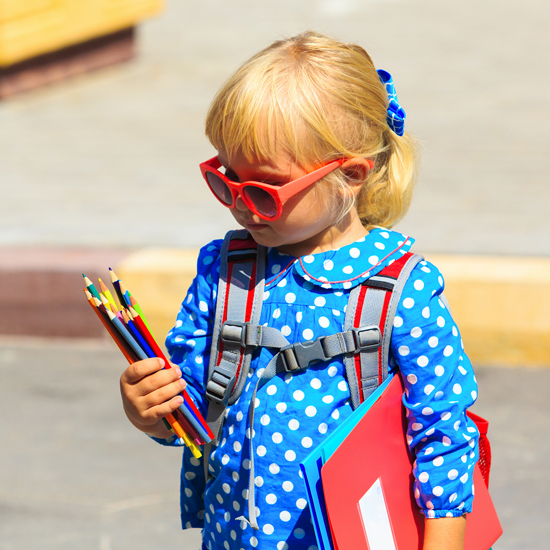 Little girl holding notebooks and pencils