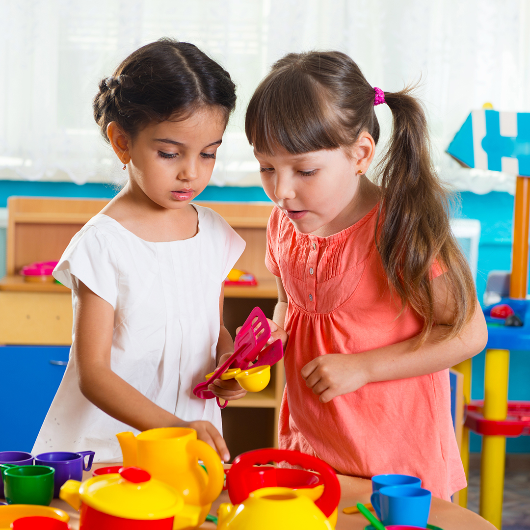 Two girls playing with toy dishes