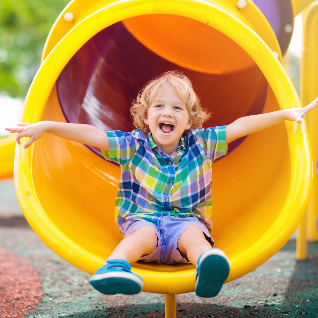 smiling kid going down slide