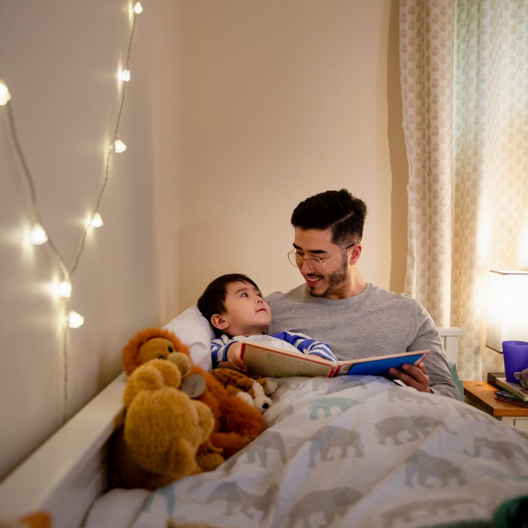 father reading son a book in bed