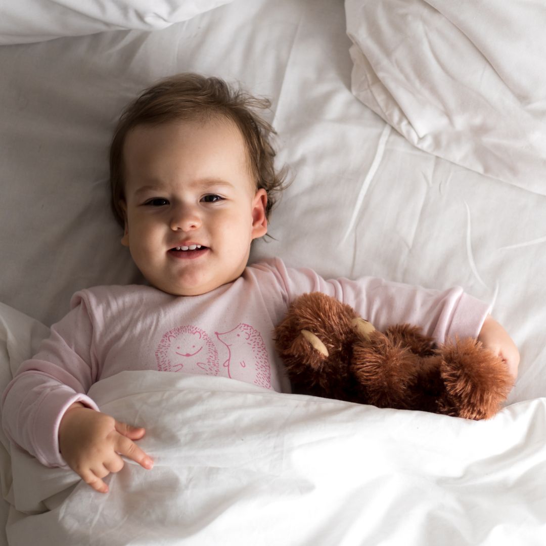 toddler tucked in bed with her stuffed animal